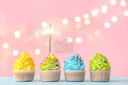 Photo for Tasty birthday cupcakes with sparkler on color background - Royalty Free Image