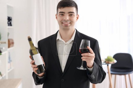 Photo for Young sommelier with bottle and glass of red wine in kitchen - Royalty Free Image