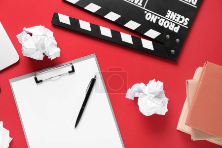 Photo for Clipboard with crumpled paper, books and movie clapper on red background - Royalty Free Image