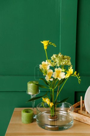 Photo for Beautiful ikebana with candles on shelf near green wall - Royalty Free Image