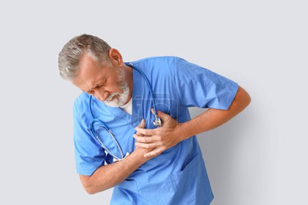 Photo for Mature doctor having heart attack on light background - Royalty Free Image
