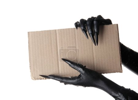 Téléchargez les photos : Mains noires de sorcière avec feuille de papier vierge sur fond blanc. Fête d'Halloween - en image libre de droit