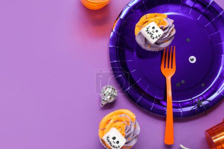 Téléchargez les photos : Ensemble de table de fête Halloween avec cupcakes sur fond violet - en image libre de droit