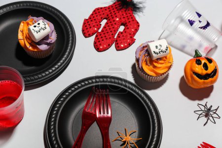 Téléchargez les photos : Cadre de table de fête avec cupcakes et décor d'Halloween sur fond blanc - en image libre de droit