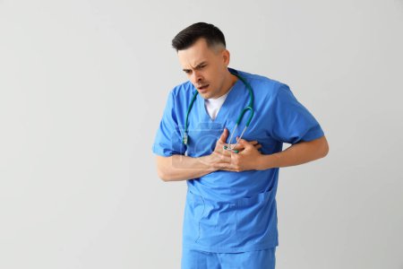 Photo for Male doctor having heart attack on light background - Royalty Free Image