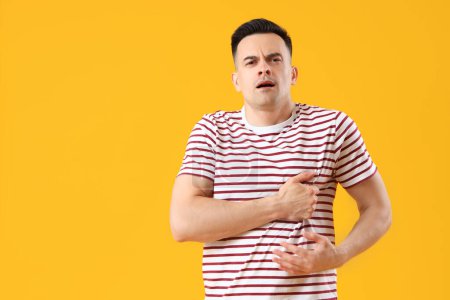 Photo for Young man having heart attack on yellow background - Royalty Free Image