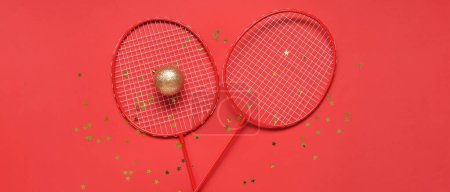 Photo for Tennis rackets with Christmas ball and confetti on red background - Royalty Free Image