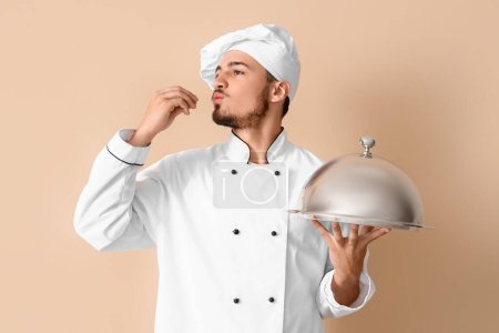 Téléchargez les photos : Chef masculin avec cloche sur fond beige - en image libre de droit