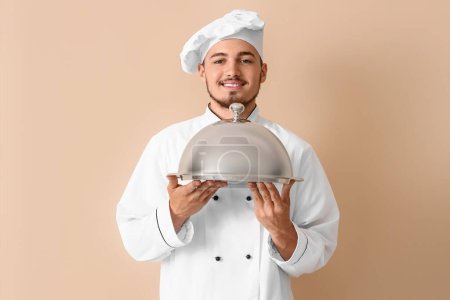 Téléchargez les photos : Chef masculin avec cloche sur fond beige - en image libre de droit
