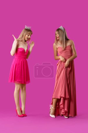 Photo for Young women dressed as dolls with tiaras on purple background - Royalty Free Image