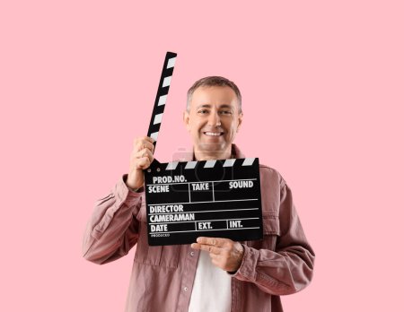 Téléchargez les photos : Acteur mature avec film clapper sur fond rose - en image libre de droit