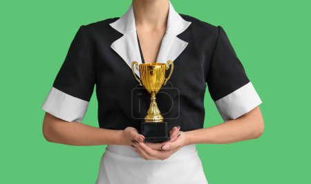 Young chambermaid with gold cup on green background, closeup
