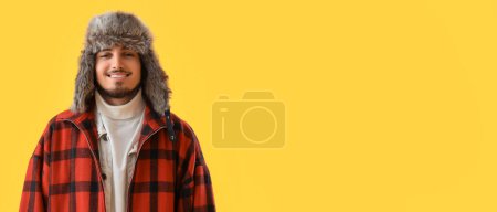 Téléchargez les photos : Jeune homme élégant en vêtements d'hiver sur fond jaune avec espace pour le texte - en image libre de droit
