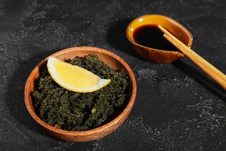Foto de Cuenco de algas sanas con rodajas de limón y salsa de soja sobre fondo oscuro - Imagen libre de derechos