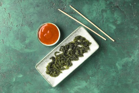 Foto de Placa con algas sanas, palillos y salsa sobre fondo verde - Imagen libre de derechos