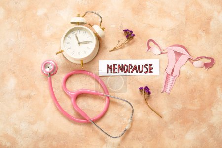 Word MENOPAUSE with flowers, stethoscope, clock and paper uterus on grunge background