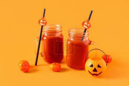 Téléchargez les photos : Citrouilles avec des verres de délicieux cocktail sanglant Mary pour la célébration d'Halloween sur fond orange - en image libre de droit