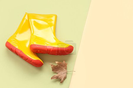Foto de Botas de goma amarillas con hoja de otoño sobre fondo colorido - Imagen libre de derechos