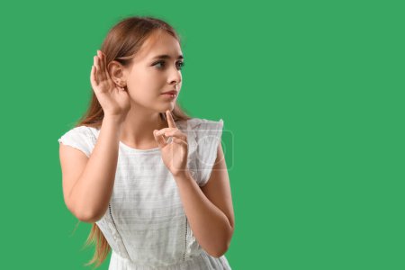 Téléchargez les photos : Adolescente essayant d'entendre quelque chose sur fond vert - en image libre de droit