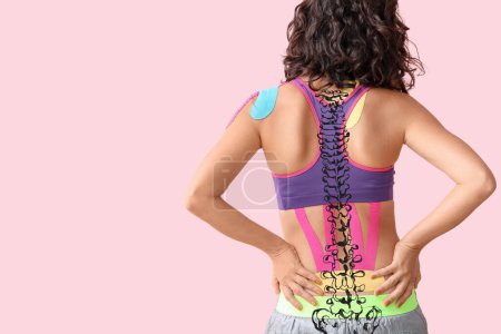 Photo for Sporty woman with physio tape applied on her back against pink background - Royalty Free Image