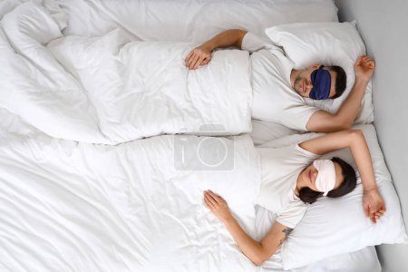 Téléchargez les photos : Jeune couple dormant avec des masques dans la chambre, vue sur le dessus - en image libre de droit