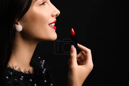 Téléchargez les photos : Belle jeune femme avec rouge à lèvres rouge sur fond noir - en image libre de droit