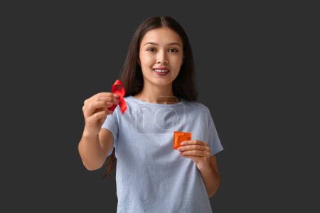 Photo for Pretty young woman with red ribbon and condom on black background. World AIDS Day concept - Royalty Free Image