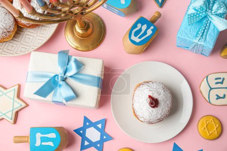 Photo for Dreidels, cookies, plate with donut and gift boxes for Hanukkah celebration on pink background - Royalty Free Image