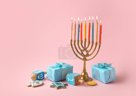 Photo for Menorah with dreidels, cookies and gift boxes for Hanukkah celebration on pink background - Royalty Free Image
