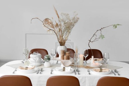 Foto de Elegante mesa con flores secas, velas y platos en casa - Imagen libre de derechos