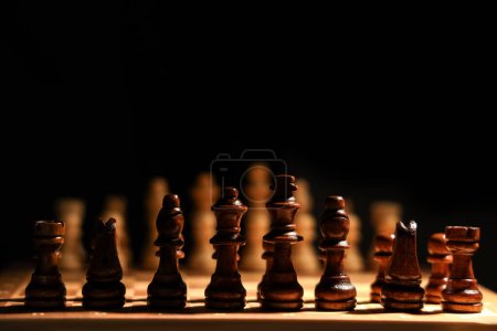 Photo for Game board with wooden chess pieces on dark background, closeup - Royalty Free Image