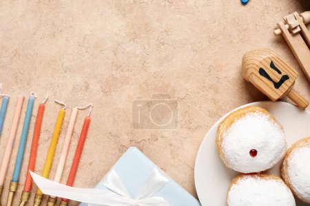 Photo for Hannukah composition with donuts, candles, gift box and dreidel on beige table, closeup - Royalty Free Image