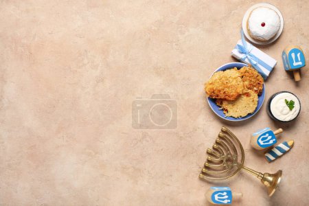 Photo for Hannukah composition with potato pancakes, menorah, dreidels and gift box on beige table - Royalty Free Image