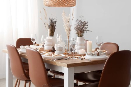 Foto de Elegante mesa con flores secas, velas encendidas y conos de pino - Imagen libre de derechos