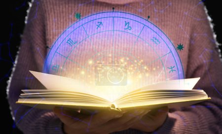 Photo for Woman reading astrology book on dark background, closeup - Royalty Free Image
