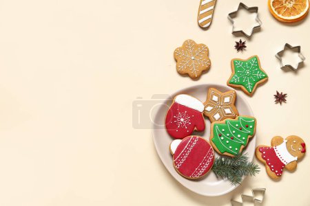 Foto de Placa con sabrosas galletas de Navidad y cortadores sobre fondo beige - Imagen libre de derechos