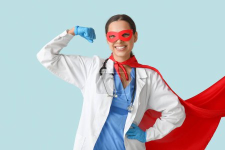 Belle femme médecin en costume de super-héros montrant les muscles sur fond bleu