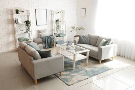 Foto de Interior del luminoso salón con acogedores sofás grises y mesa de centro - Imagen libre de derechos