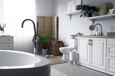Foto de Interior del baño de luz con inodoro de cerámica, lavabo y armarios de tocador - Imagen libre de derechos