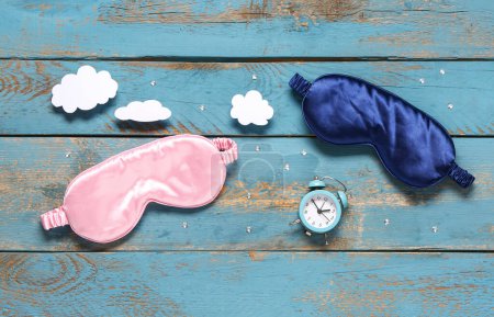 Photo for Composition with sleep masks, paper clouds and alarm clock on color wooden background - Royalty Free Image