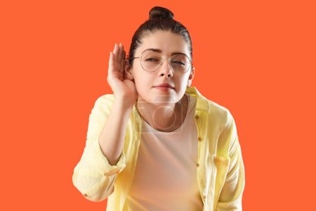 Photo for Young gossip woman trying to hear something on orange background, closeup - Royalty Free Image
