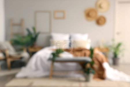 Téléchargez les photos : Vue floue de la chambre confortable avec lit confortable et banc gris - en image libre de droit
