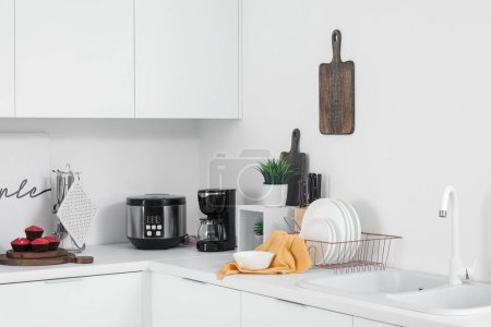 Comptoirs de cuisine blancs avec machine à café, cuisinière multi et ustensiles
