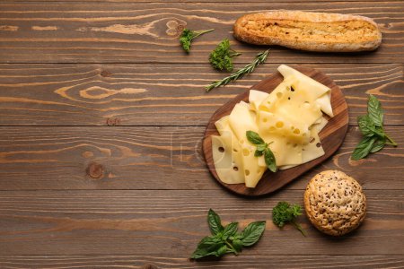 Board with tasty cheese slices and bread on wooden background
