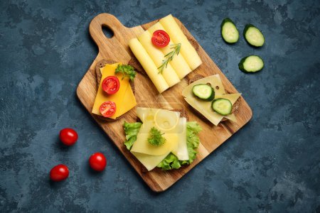 Tasty sandwiches with cheese, tomatoes and cucumber in board on blue background