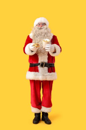 Photo for Santa Claus with tasty burger and french fries on yellow background - Royalty Free Image