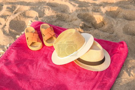 Téléchargez les photos : Serviette avec chapeaux de paille élégants et tongs sur sable - en image libre de droit