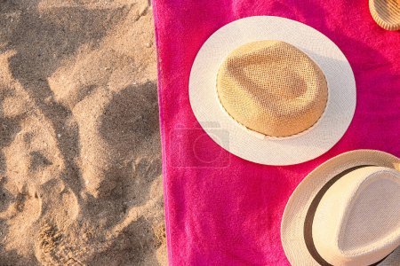 Téléchargez les photos : Serviette avec des chapeaux de paille élégants sur le sable - en image libre de droit