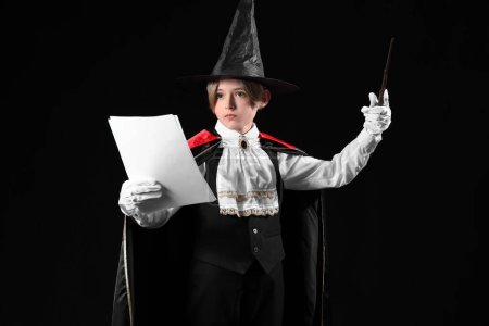 Téléchargez les photos : Petit acteur habillé en magicien avec scénario de film sur fond sombre - en image libre de droit