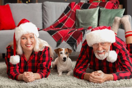 Foto de Feliz pareja madura con Jack Russell terrier y regalo de Navidad en casa - Imagen libre de derechos